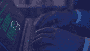 What is vibe coding: hands typing code on a laptop with an AI chat icon representing AI-assisted development.